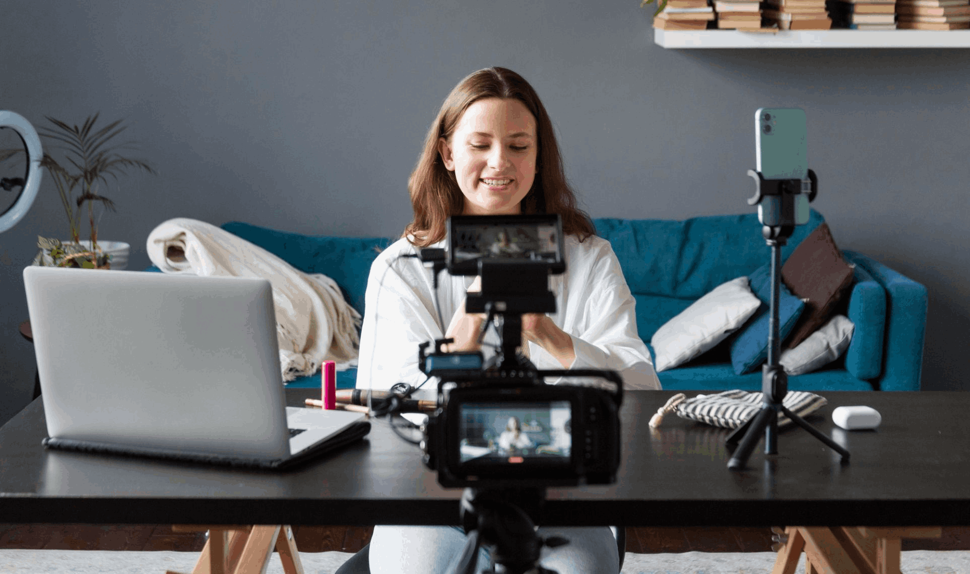 Person recording herself with multiple cameras and a smartphone setup at a desk, creating Video & Multimedia Content.